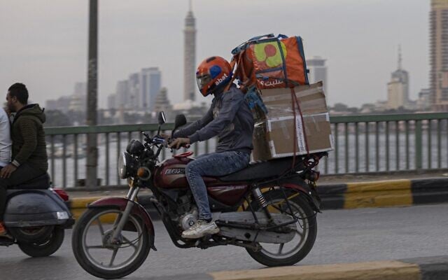 Un livreur roule sur sa moto dans la capitale égyptienne, Le Caire, le 21 avril 2022, pendant le mois sacré musulman du Ramadan. (Crédit : Khaled DESOUKI / AFP) Un livreur roule sur sa moto dans la capitale égyptienne, Le Caire, le 21 avril 2022, pendant le mois sacré musulman du Ramadan. (Crédit : Khaled DESOUKI / AFP)