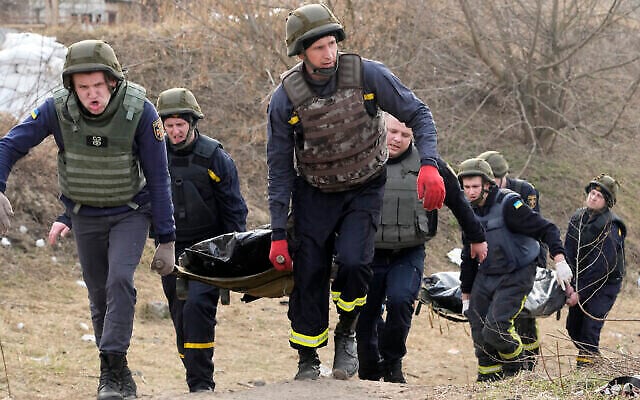 Les services d’urgence ukrainiens transportent les corps de civils tués par les troupes russes sur le pont détruit à Irpin près de Kiev, en Ukraine, le 31 mars 2022. (Crédit : AP Photo/Efrem Lukatsky)