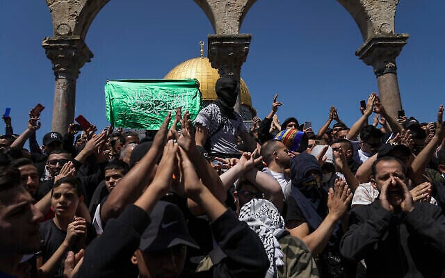 Des Palestiniens scandant des slogans et agitant des drapeaux du Hamas lors d'une manifestation contre Israël, devant le Dôme du Rocher, dans l'enceinte de la mosquée Al-Aqsa, au sommet du mont du Temple, dans la Vieille Ville de Jérusalem, le 15 avril 2022. (Crédit : AP Photo/Mahmoud Illean)