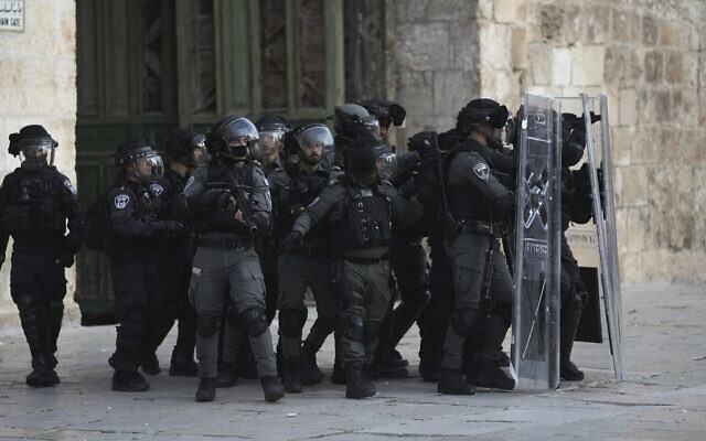 La police israélienne se déplace derrière des boucliers anti-émeutes lors d’affrontements avec des Palestiniens dans l’enceinte du mont du Temple, dans la Vieille Ville de Jérusalem, le 22 avril 2022. (Crédit : AP Photo/Mahmoud Illean)