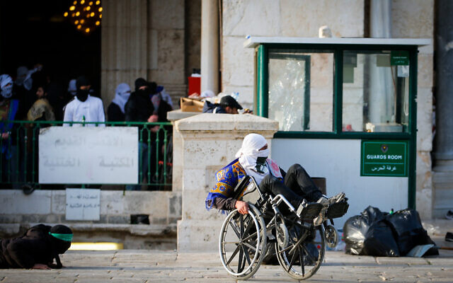 Un Palestinien masqué en fauteuil roulant prend part à des affrontements entre Palestiniens et la police israélienne au mont du Temple, dans la Vieille Ville de Jérusalem, le 22 avril 2022. (Crédit : Jamal Awad/Flash90)