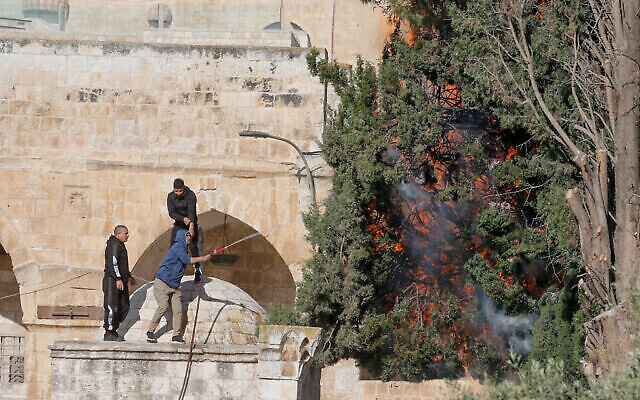 Des Palestiniens tentent d’éteindre un incendie qui a éclaté lors d’affrontements entre Palestiniens et la police israélienne, au mont du Temple, dans la Vieille Ville de Jérusalem, le 22 avril 2022. (Crédit : Jamal Awad/Flash90)