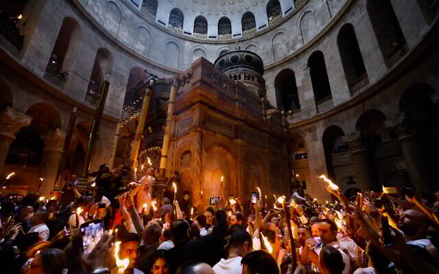 Des pèlerins chrétiens tiennent des bougies alors qu'ils se rassemblent pendant la cérémonie du feu sacré à l'église du Saint-Sépulcre, dans la Vieille Ville de Jérusalem, le 23 avril 2022. (Crédit : Maya Alleruzzo/AP Photo) Des pèlerins chrétiens tiennent des bougies alors qu'ils se rassemblent pendant la cérémonie du feu sacré à l'église du Saint-Sépulcre, dans la Vieille Ville de Jérusalem, le 23 avril 2022. (Crédit : Maya Alleruzzo/AP Photo)