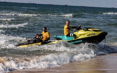 Des sauveteurs simulent une noyade sur une plage de la ville côtière méditerranéenne d'Ashdod, le 14 février 2022, alors qu'ils font la démonstration du programme d'intelligence artificielle visant à détecter les menaces de noyade. (Crédit : MENAHEM KAHANA / AFP)