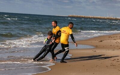 Des sauveteurs simulent une noyade sur une plage de la ville côtière méditerranéenne d'Ashdod, le 14 février 2022, alors qu'ils font la démonstration du programme d'intelligence artificielle visant à détecter les menaces de noyade. (Crédit : MENAHEM KAHANA / AFP)