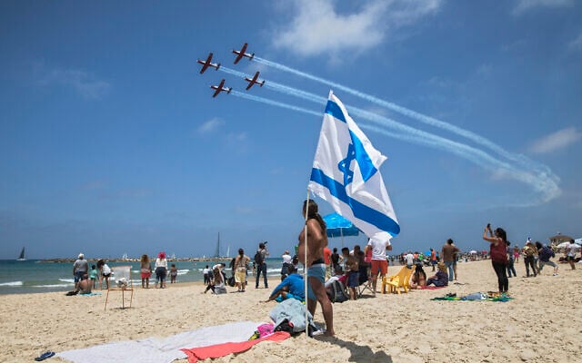 Dossier : Des personnes sur une plage de Tel Aviv regardent un spectacle aérien militaire lors de Yom HaAstmaout, le 2 mai 2017. (Crédit: AP Photo/Dan Balilty) Dossier : Des personnes sur une plage de Tel Aviv regardent un spectacle aérien militaire lors de Yom HaAstmaout, le 2 mai 2017. (Crédit: AP Photo/Dan Balilty)