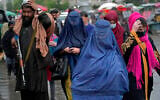 Des femmes afghanes marchent dans le vieux marché alors qu’un combattant taliban monte la garde, au centre-ville de Kaboul, en Afghanistan, le mardi 3 mai 2022. Le samedi 7 mai, les dirigeants talibans de l’Afghanistan ont ordonné à toutes les Afghanes de porter des vêtements de la tête aux pieds en public. (Crédit : AP Photo/Ebrahim Noroozi)
