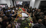 Des Palestiniens encerclent la dépouille  de la journaliste palestinienne d'Al Jazeera, Shireen Abu Akleh, conduite au siège de la chaîne d’information à Ramallah, en Cisjordanie, le 11 mai 2022. (Crédit : Abbas Momani/Pool via AP)