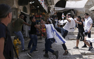 Palestiniens et jeunes juifs s’affrontent dans la Vieille Ville de Jérusalem alors que les Israéliens célèbrent Yom Yeroushalayim, fête célébrant la prise de la Vieille Ville pendant la guerre des six jours en 1967, le 29 mai 2022. (Crédit : AP Photo/Ariel Schalit)