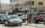 Un Israélien retire un drapeau palestinien d’un lampadaire dans la ville de Hawara, en Cisjordanie, près de Naplouse, le 22 mai 2022 (Crédit : Nasser Ishtayeh/Flash90)