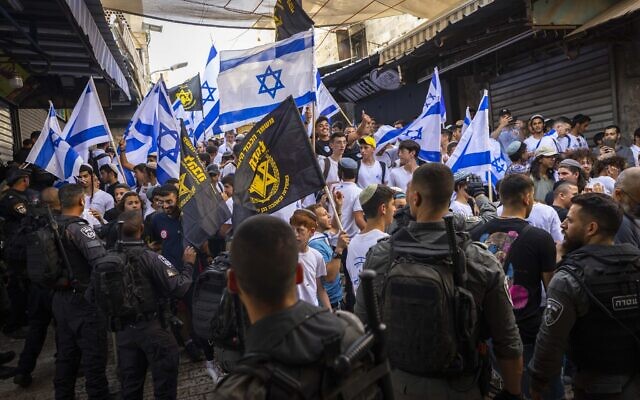 Des membres du groupe d'extrême-droite Lehava brandissent le drapeau de leur organisation à côté de drapeaux israéliens pendant une marche dans le quartier musulman de la Vieille Ville de Jérusalem, le 29 mai 2022. (Crédit : Olivier Fitoussi/Flash90) Des membres du groupe d'extrême-droite Lehava brandissent le drapeau de leur organisation à côté de drapeaux israéliens pendant une marche dans le quartier musulman de la Vieille Ville de Jérusalem, le 29 mai 2022. (Crédit : Olivier Fitoussi/Flash90)