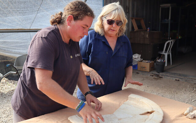 La docteure de l'Autorité israélienne des Antiquités Tali Erickson-Gini, à droite, examine un plateau de marbre trouvé près de l'autel d'une ancienne église byzantine, près d'Ashkelon. (Crédit : Anat Rasiuk, Israel Antiquities Authority)
