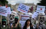 Des réservistes des forces de défense israéliennes, portant des masques à l'effigie de Yahya Sinwar, chef du Hamas dans la bande de Gaza, et tenant des drapeaux palestiniens, manifestent devant les bureaux des Nations unies à Genève, le 7 juin 2022. (Crédit : Fabrice COFFRINI / AFP)