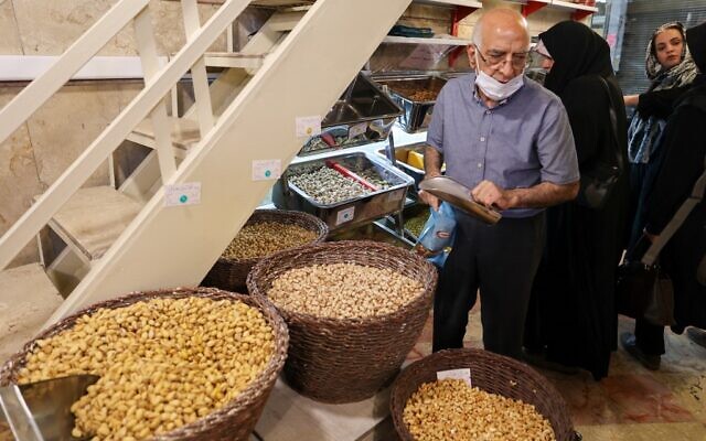 Un employé du plus ancien grossiste en pistaches d'Iran prépare une commande pour les clients du magasin dans le célèbre Graz Bazar de Téhéran, le 19 juin 2022. (Crédit : ATTA KENARE / AFP) Un employé du plus ancien grossiste en pistaches d'Iran prépare une commande pour les clients du magasin dans le célèbre Graz Bazar de Téhéran, le 19 juin 2022. (Crédit : ATTA KENARE / AFP)