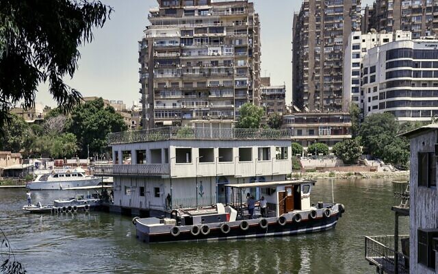 L'un des maisons flottantes habituellement amarrés sur l'une des rives du Nil entre le quartier de Zamalek, au Caire, la capitale égyptienne (à droite), et le quartier d'Agouza, dans la ville jumelle de Gizeh (à gauche), est remorqué par les autorités le 27 juin 2022, dans le cadre d'un décret plus large visant à nettoyer toutes les rives du fleuve dans la région. (Crédit : Khaled DESOUKI / AFP) L'un des maisons flottantes habituellement amarrés sur l'une des rives du Nil entre le quartier de Zamalek, au Caire, la capitale égyptienne (à droite), et le quartier d'Agouza, dans la ville jumelle de Gizeh (à gauche), est remorqué par les autorités le 27 juin 2022, dans le cadre d'un décret plus large visant à nettoyer toutes les rives du fleuve dans la région. (Crédit : Khaled DESOUKI / AFP)