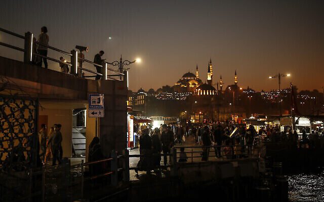Illustration : Avec en toile de fond la mosquée Suleymaniye, des passants flânent le long des rives du Bosphore à Istanbul, en Turquie, le 23 octobre 2020. (Crédit : AP Photo/Emrah Gurel)