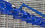 Photo d'illustration : Un ouvrier sur une grue ajuste les drapeaux de l’UE devant le siège de l’UE à Bruxelles, le 23 juin 2016. (Crédit : AP Photo/Virginia Mayo, Archive)
