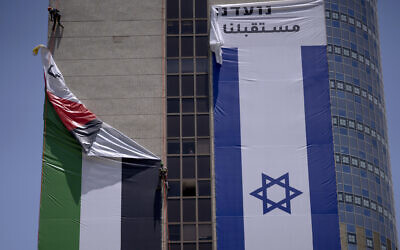 Un drapeau palestinien est retiré d'un bâtiment par les autorités israéliennes après avoir été mis en place par un groupe de défense qui promeut la coexistence entre Palestiniens et Israéliens, à Ramat Gan, le 1er juin 2022. (Crédit : AP Photo/Oded Balilty)