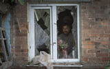 Un habitant place un vase avec des fleurs sur une fenêtre brisée de sa maison endommagée par les bombardements russes à Bakhmut, dans la région de Donetsk, en Ukraine, dimanche 26 juin 2022 (AP Photo/Efrem Lukatsky).