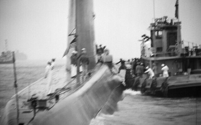Le contre-amiral Hyman Rickover, pionnier du développement de sous-marins atomiques, monte à bord du sous-marin de la Marine à propulsion nucléaire Nautilus depuis un remorqueur, dans le port de New York, le 25 août 1958. (Crédit : AP Photo)