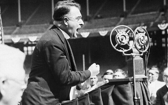 Le révérend Charles E. Coughlin, de Détroit, Michigan, s'adressant à un grand rassemblement de ses fidèles à Cleveland, dans l'Ohio, le 11 mai 1936. Il a plaidé pour le soutien des candidats du N.U.S.J. dans les primaires de l'Ohio du mardi. (Crédit : AP)