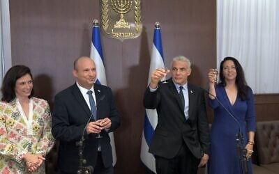 Le Premier ministre sortant Naftali Bennett,à gauche, et son remplaçant, le nouveau Premier ministre Yair Lapid, ainsi que leurs épouses, lors d'une cérémonie de passation de pouvoirs au bureau du Premier ministre à Jérusalem. (Crédit: Haim Zach/GPO)