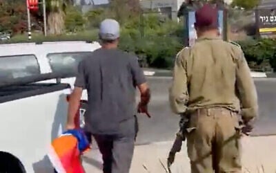 Deux hommes, dont un en uniforme de Tsahal, en train de retirer un drapeau de la Gay Pride, dans le nord d’Israël le 23 juin 2022. (Crédit : Capture d’écran)