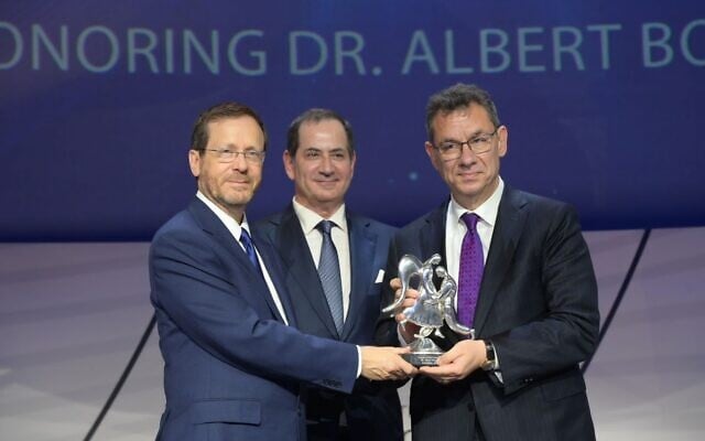 Le Dr Albert Bourla, à droite, reçoit le prix Genesis 2022 des mains du président israélien Isaac Herzog, à gauche, et de Stan Polovets, cofondateur et président-directeur général de la fondation du prix Genesis. (Crédit: Amos Ben-Gershom/GPO) Le Dr Albert Bourla, à droite, reçoit le prix Genesis 2022 des mains du président israélien Isaac Herzog, à gauche, et de Stan Polovets, cofondateur et président-directeur général de la fondation du prix Genesis. (Crédit: Amos Ben-Gershom/GPO)