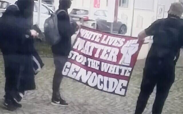 Des hommes portent une bannière d’extrême droite lors d’une manifestation devant la synagogue d’Ulm, en Allemagne, le 5 juin 2022. (Crédit : Avec l’aimable autorisation de la Communauté religieuse juive de Wurtemberg)