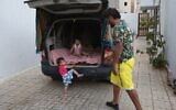 Mahmud Aguil est assis avec ses enfants à l'arrière de sa camionnette climatisée, garée devant sa maison à Tripoli, la capitale de la Libye, le 5 juillet 2022. - Mahmud Aguil, 48 ans, qui possède une maison confortable dans le centre de Tripoli, a été contraint de dormir avec ses deux enfants à l'arrière de sa camionnette climatisée car il subit des coupures de courant pouvant aller jusqu'à 18 heures par jour. (Crédit : Mahmud Turkia / AFP)