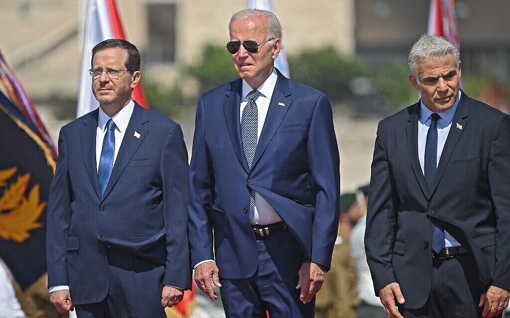 Le président Isaac Herzog, son homologue américain Joe Biden et le Premier ministre Yair Lapid écoutent les hymnes nationaux à l'aéroport Ben Gurion, le 13 juillet 2022. (Crédit : MANDEL NGAN / AFP)