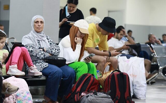 Des passagers sont assis dans une salle d'attente du côté jordanien du pont Allenby qui traverse la Cisjordanie et la Jordanie, le 19 juillet 2022. (Crédit : Khalil MAZRAAWI / AFP)