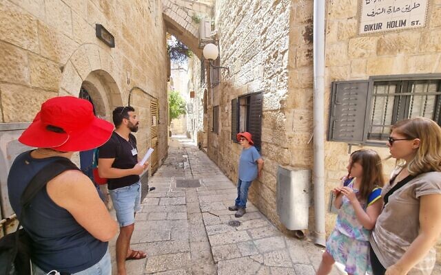 Le guide touristique Idan Pinhas montre aux participants le site du premier hôpital Bikur Holim dans la Vieille Ville de Jérusalem, en juin 2022. (Crédit : Shmuel Bar-Am)