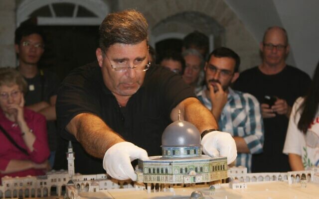 Le Dr Eyal Meron soulève le toit d'un site de la maquette de Conrad Schick dans la Vieille Ville de Jérusalem, juin 2022. (Crédit : Shmuel Bar-Am)