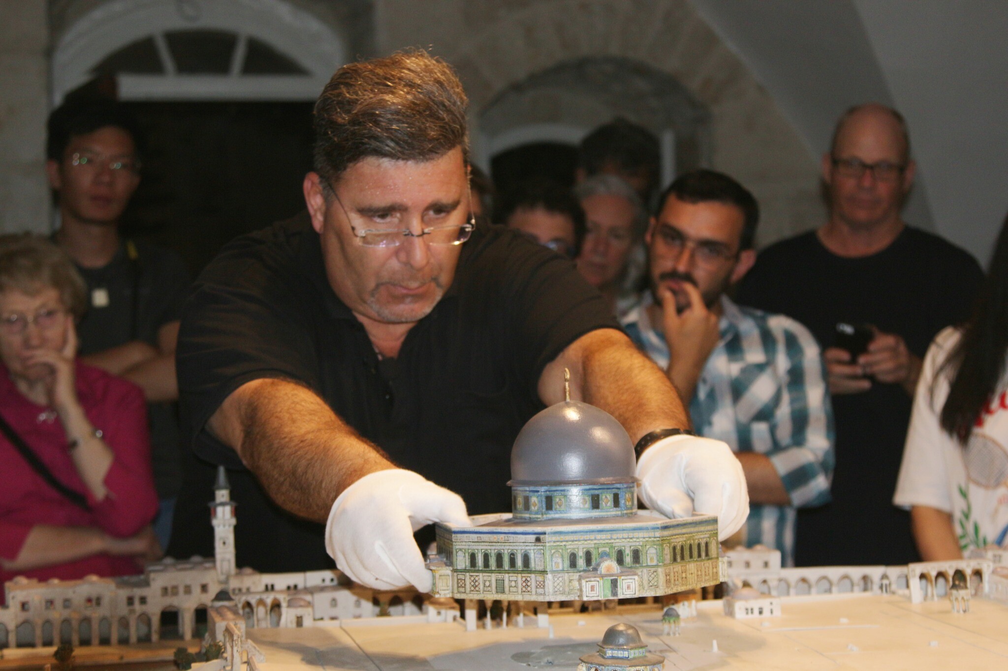 Le Dr Eyal Meron soulève le toit d'un site de la maquette de Conrad Schick dans la Vieille Ville de Jérusalem, juin 2022. (Crédit : Shmuel Bar-Am)