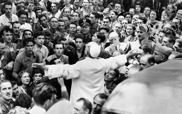 Hommes, femmes et soldats se rassemblent autour du Pape Pie XII, les bras tendus, le 15 octobre 1943, lors d'une tournée dans Rome, en Italie, après un raid aérien américain. (Crédit : AP Photo, dossier)