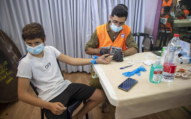 Illustration : Un soldat israélien effectue un test d’anticorps contre la COVID-19 sur un jeune garçon à Hadera, en Israël, le lundi 23 août 2021. (Crédit : AP Photo/Ariel Schalit) Illustration : Un soldat israélien effectue un test d’anticorps contre la COVID-19 sur un jeune garçon à Hadera, en Israël, le lundi 23 août 2021. (Crédit : AP Photo/Ariel Schalit)