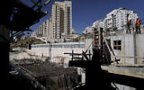 Des ouvriers palestiniens travaillent sur un site de construction dans un nouveau projet de logement à Har Homa, à Jérusalem-Est, le 6 juillet 2022. (Crédit : AP Photo/Mahmoud Illean)