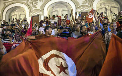 Des Tunisiens célèbrent les sondages de sortie des urnes indiquant un vote en faveur de la nouvelle Constitution, à Tunis, le lundi 25 juillet 2022. (Crédit : AP/Riadh Dridi)