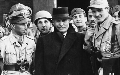 Le dictateur italien Benito Mussolini, au centre, quitte l’hôtel Gran Sasso dans les Abruzze, au nord de Rome, le 2 octobre 1943, où il a été emprisonné après sa chute. Il est entouré de parachutistes allemands qui l’ont libéré. (Crédit : AP Photo)