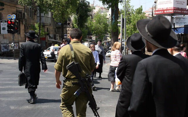 Illustration : Des hommes juifs ultra-orthodoxes du quartier de Mea Shearim à Jérusalem marchent aux côtés d'un soldat israélien, le 6 juin 2008. (Crédit : Lara Savage/Flash 90) Illustration : Des hommes juifs ultra-orthodoxes du quartier de Mea Shearim à Jérusalem marchent aux côtés d'un soldat israélien, le 6 juin 2008. (Crédit : Lara Savage/Flash 90)
