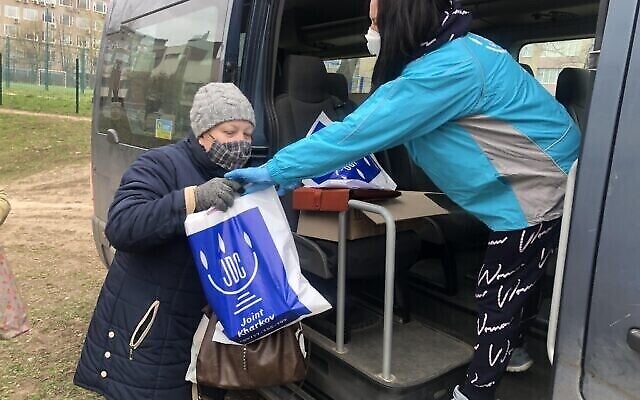 Une employée de l'AJC donne des produits alimentaires à un membre de la communauté juive de Kharkiv, en Ukraine. (Crédit : Avec l'aimable autorisation du JDC) Une employée de l'AJC donne des produits alimentaires à un membre de la communauté juive de Kharkiv, en Ukraine. (Crédit : Avec l'aimable autorisation du JDC)
