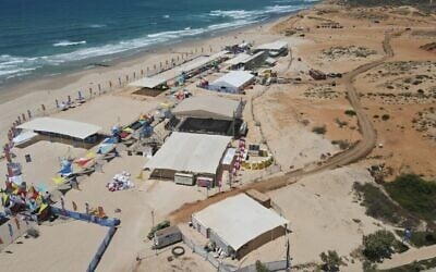 Vue aérienne du complexe des Maccabiades sur la plage de Poleg, à Netanya, le 11 juillet 2022. La route d’accès à travers les dunes se trouve à droite. (Crédit : Rika Edelman)