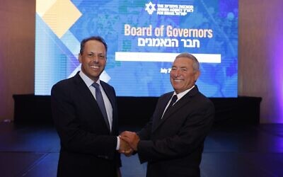 Le nouveau président du conseil d’administration de l’Agence juive, Mark Wilf, à gauche, serrant la main du nouveau président de l’exécutif de l’Agence juive, Doron Almog, après leur élection, le 10 juillet 2022. (Crédit : Olivier Fitoussi/Jewish Agency)