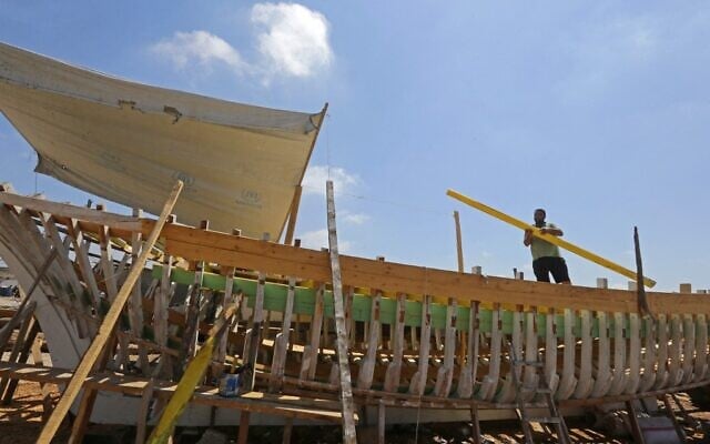 L'artisan syrien Khaled Bahlawan construit un bateau en bois dans son chantier naval sur l'île méditerranéenne d'Arwad, en Syrie, le 24 juillet 2022. (Crédit : LOUAI BESHARA / AFP)