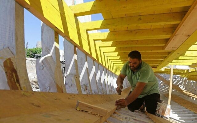 L'artisan syrien Khaled Bahlawan martèle des clous sur un bateau en bois dans son chantier naval sur l'île méditerranéenne d'Arwad, en Syrie, le 24 juillet 2022. (Crédit : LOUAI BESHARA / AFP)