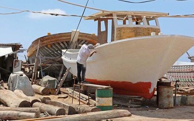 Des membres de la famille Bahlawan construisent des bateaux dans leur chantier naval sur l'île méditerranéenne d'Arwad, en Syrie, le 24 juillet 2022. (Crédit : LOUAI BESHARA / AFP)