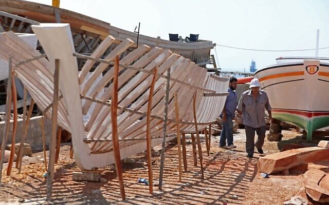 Des membres de la famille Bahlawan construisent des bateaux dans leur chantier naval sur l'île méditerranéenne d'Arwad, en Syrie, le 24 juillet 2022. (Crédit : LOUAI BESHARA / AFP)
