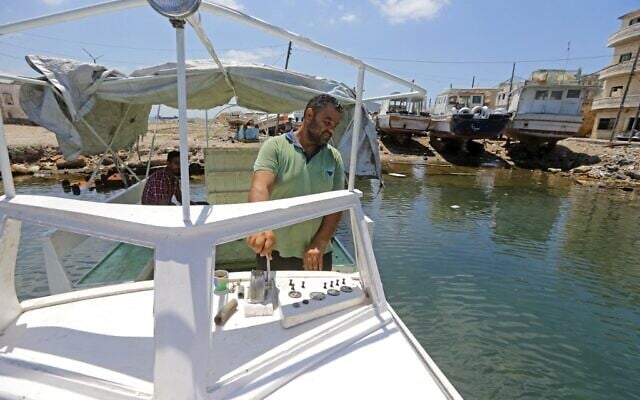 L'artisan syrien Khaled Bahlawan monte sur son bateau dans l'île méditerranéenne d'Arwad, en Syrie, le 24 juillet 2022. (Crédit : LOUAI BESHARA / AFP)