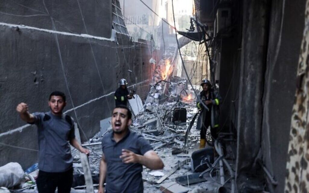 Des sauveteurs et des pompiers éteignent un incendie après une frappe aérienne israélienne sur la ville de Gaza, le 5 août 2022. (Crédit : Mohammed ABED / AFP)
